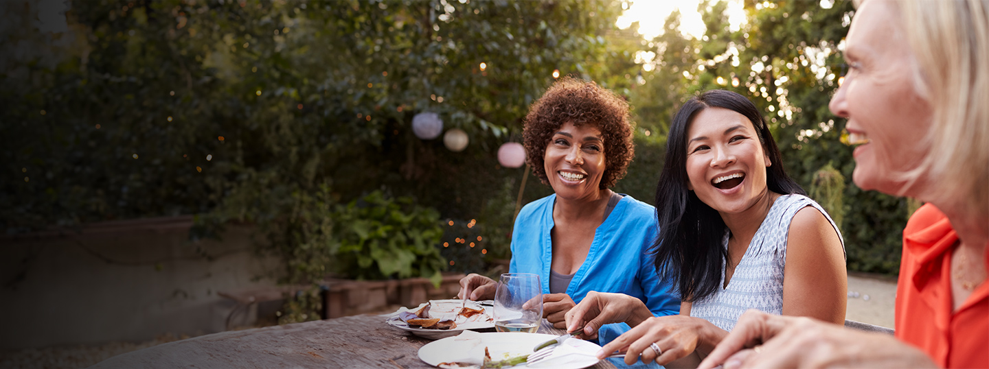 three women sitting at table smiling and laughing